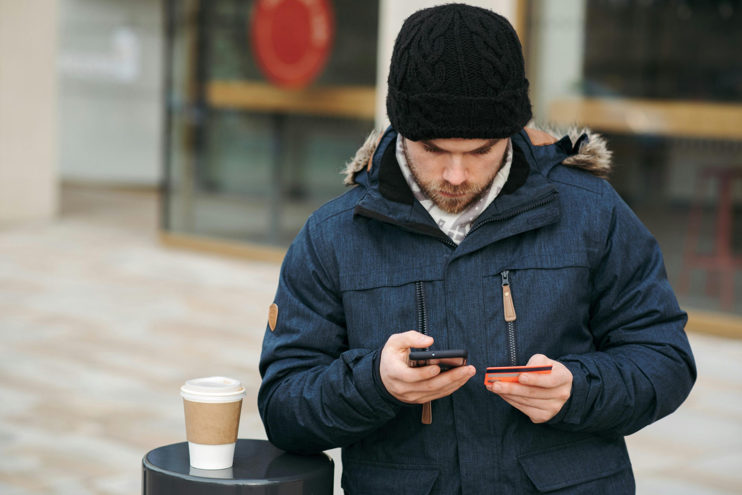 Mann In Schwarzer Strickmütze Und Schwarzer Jacke, Die Smartphone Hält